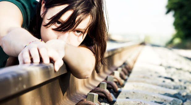 woman lying on railroad tracks