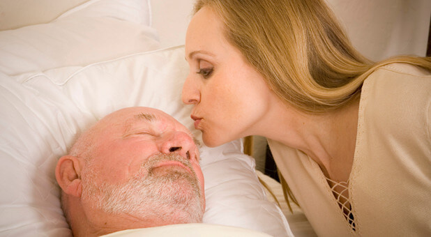 woman kissing sick man in hospital bed