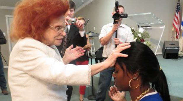 Evangelist Verna Linzey prays for a young woman.