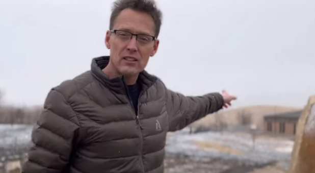 Pastor Matt Carlson points to the burnt area extending up to his church, Dec. 31, 2021.